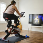 在室内运动自行车上使用数字健身的女人