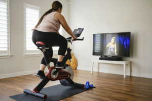 在室内运动自行车上使用数字健身的女人