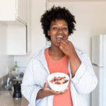 女人在厨房吃健康的早餐来使用技巧来减少卡路里