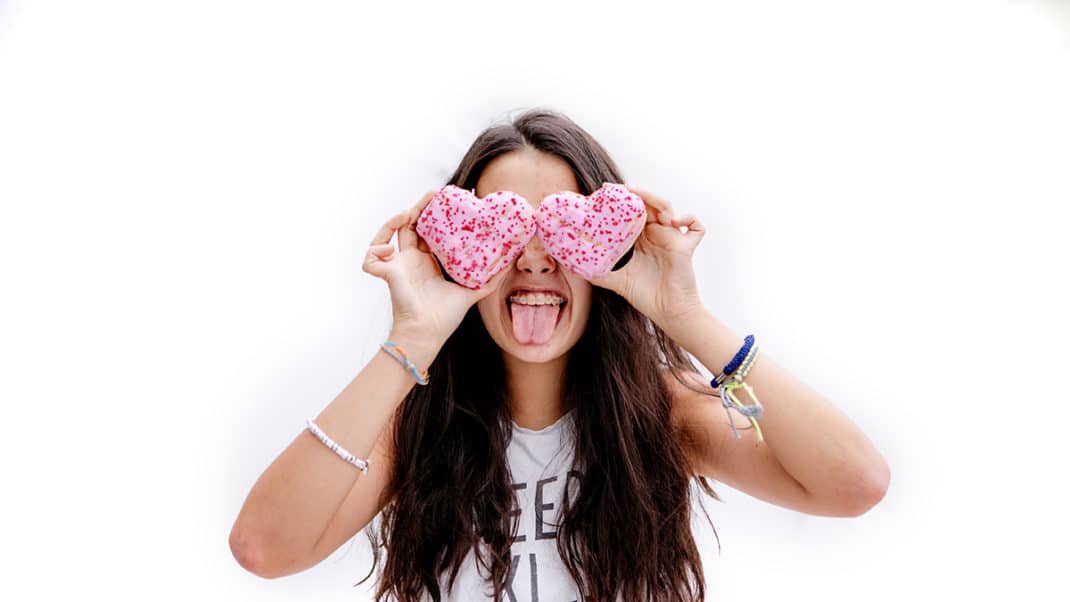 女孩伸出舌头，举起饼干来证明糖和行为障碍之间的联系