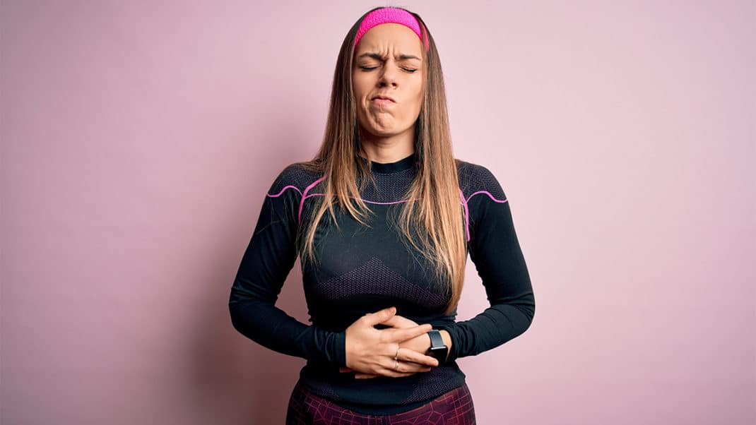 一名女子抱着自己的肚子，展示肠道微生物群和运动表现之间的联系