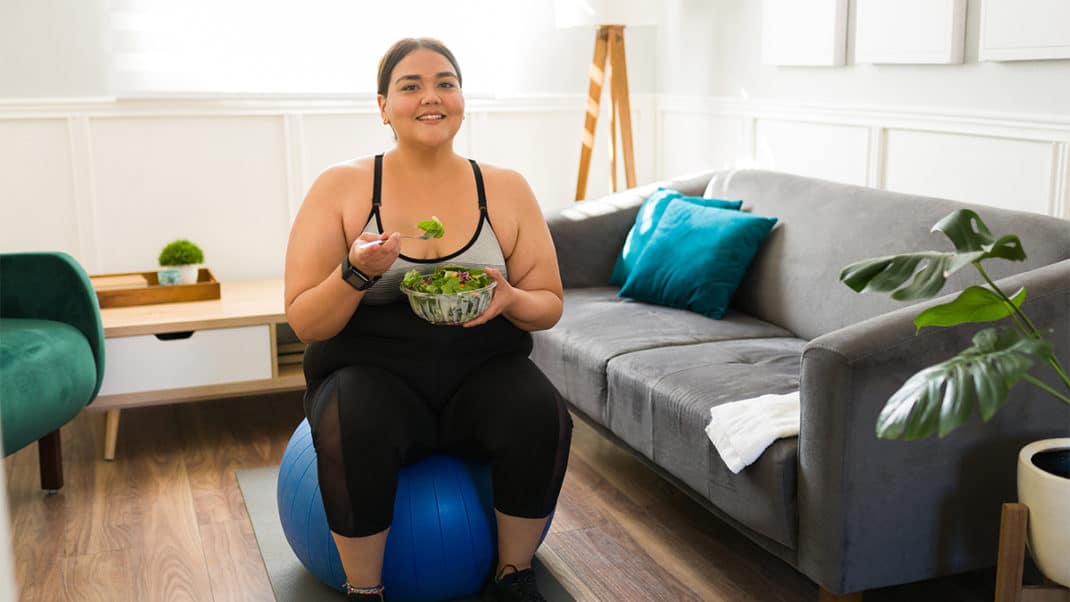 有健康饮食和锻炼习惯的妇女坐在球上吃沙拉