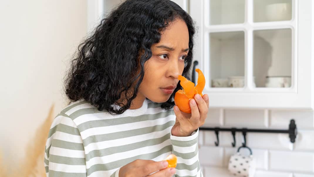 一名女子闻橘子皮来显示因新冠肺炎失去味觉和气味