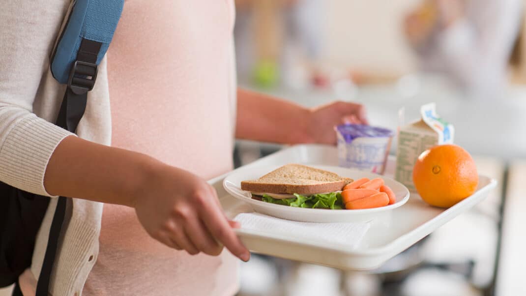 在美国，一个孩子拿着午餐托盘，代表着与饥饿作斗争
